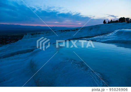 トルコ　夕暮れ時のヒエラポリス・パムッカレの石灰棚と青い水面 95026906