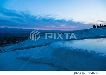 トルコ　夕暮れ時のヒエラポリス・パムッカレの石灰棚と青い水面 95026909