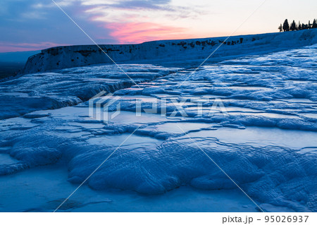 トルコ　夕暮れ時のヒエラポリス・パムッカレの鍾乳石と青い水面 95026937