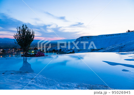 トルコ　夕暮れ時のヒエラポリス・パムッカレの石灰棚と青い水面 95026945
