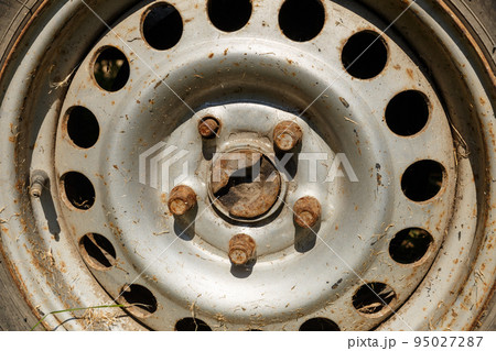 old rusty wheel in the sunlight. wheel rim, bolts and capped schrader valve. Close-up old rusty wheel in the sunlight. wheel rim, bolts and capped schrader valve. Close-up 95027287