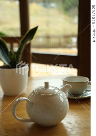 Teapot, cup and plant on wooden table in restaurant Teapot, cup and plant on wooden table in restaurant 95027609