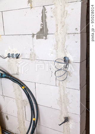 Electrical wiring concept background. The electrical box with wires is mounted in the wall. Electrical wiring concept background. The electrical box with wires is mounted in the wall. 95028014