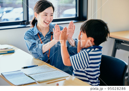 ハイタッチする塾講師と小学生の男の子 95028286