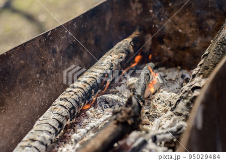 barbecue in the Park. natural wood glow in the grill, the coals are covered with ashes, the flame burns dry wood. 95029484