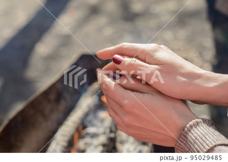 barbecue in the Park. a girl warms his hands by the fire, natural wood smolder in the grill, the coals are covered with ash 95029485