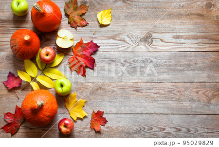 Autumn border from apples, pumpkin and fallen leaves on old wooden table. 95029829