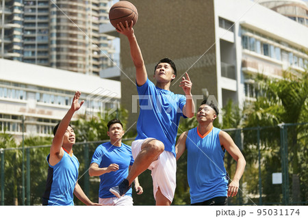 young asian adult male player playing basketball on a urban outdoor court young asian adult male player playing basketball on a urban outdoor court 95031174