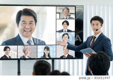 大型モニターに映る外部講師と司会をする男性　ビジネスセミナー 95031447