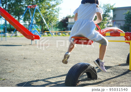 公園でシーソーに乗っている小学3年生の女の子。小学生の夏休みの外遊び。 95031540