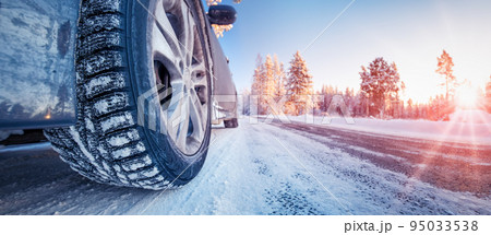 Closeup view of the car's wheel on the snowy road in natural park Closeup view of the car's wheel on the snowy road in natural park 95033538