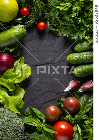 Variety of fresh vegetables on black slate background table. Salad ingredients at tabletop 95033949