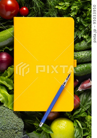 Variety of fresh vegetables and cookbook on table background. Cookig concept and salad ingredients 95033950