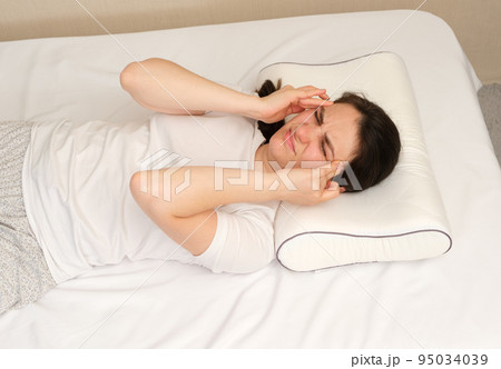 The woman woke up with a headache, a morning migraine or an improperly selected pillow. The woman woke up with a headache, a morning migraine or an improperly selected pillow. 95034039