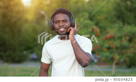 African American man in headphones listens to music in park 95034823