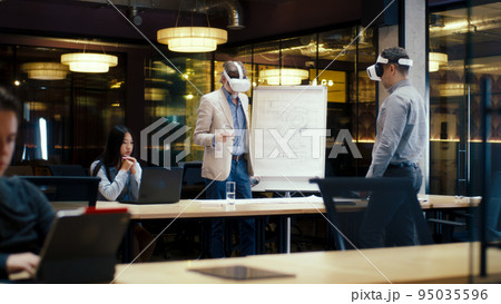 Engineers examining blueprint in VR headsets Engineers examining blueprint in VR headsets 95035596