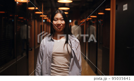 Asian woman standing in office corridor Asian woman standing in office corridor 95035641