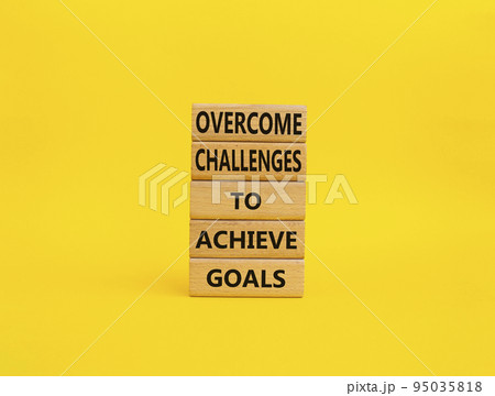 Challenges or goals symbol. Wooden blocks with words 'Overcome challenges to achieve goals'. Beautiful yellow background. Business and 'Overcome challenges to achieve goals' concept. Copy space. Challenges or goals symbol. Wooden blocks with words 'Overcome challenges to achieve goals'. Beautiful yellow background. Business and 'Overcome challenges to achieve goals' concept. Copy space. 95035818