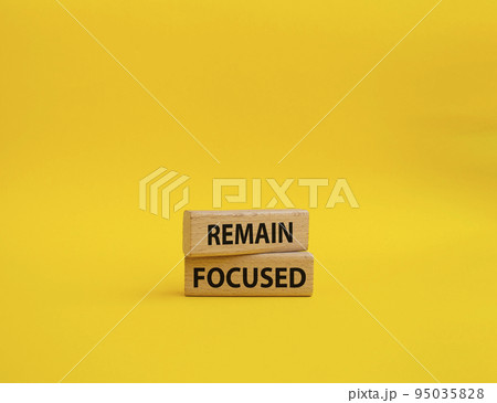 Remain focused symbol. Concept words Remain focused on wooden blocks. Beautiful yellow background. Business and Remain focused concept. Copy space. 95035828