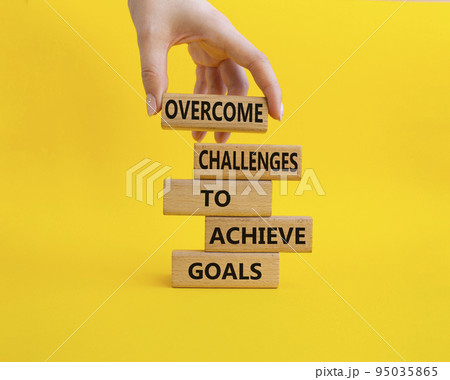 Challenges or goals symbol. Wooden blocks with words Overcome challenges to achieve goals. Beautiful yellow background. Businessman hand. Overcome challenges to achieve goals concept. Copy space 95035865