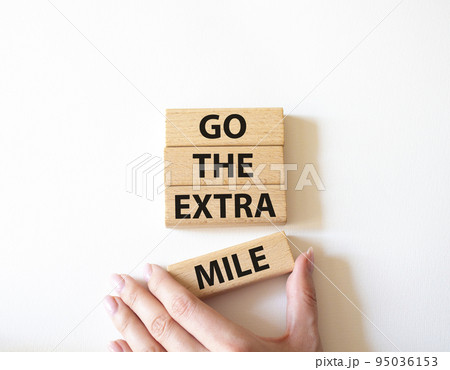 Go the extra mile symbol. Wooden blocks with words Go the extra mile. Beautiful white background. Businessman hand. Business and Go the extra mile concept. Copy space. 95036153