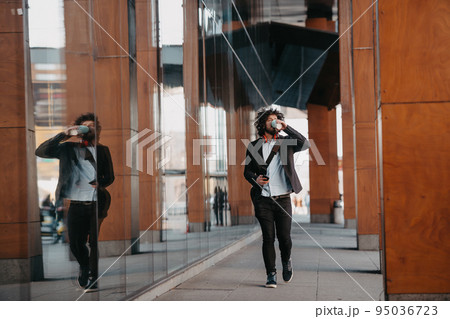 Trendy businessman with leather briefcase in financial district using smartphone while listening audio songs headphones drinking coffee 95036723