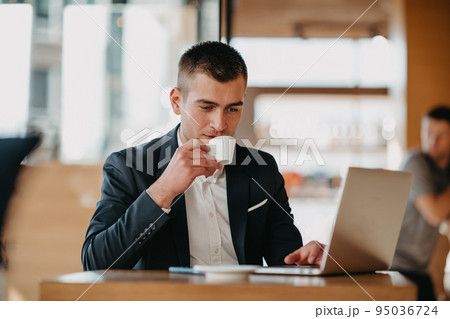 Happy business man sitting at cafeteria with laptop and smartphone 95036724