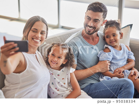 Family selfie, interracial smile and parents with phone for social media with children, happy on the sofa in house and relax with kids in home. Girl siblings taking photo with mother and father 95038334