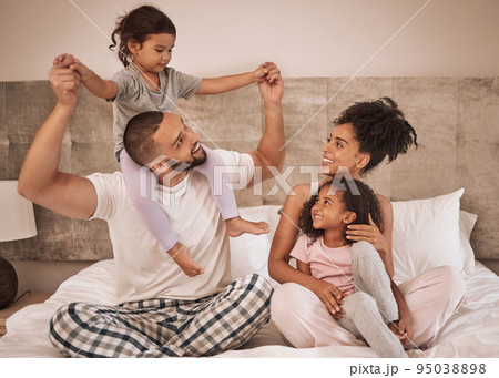 Family morning, bed relax and parents happy with children in bed, smile in bedroom of house and love for kids in home together. Girl siblings playing and bonding in happiness with mother and father 95038898