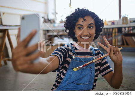 Indian woman artist, selfie with paint brush and art on floor of studio workshop to share to social media. Portrait of happy, creative professional painter and smiling after oil or watercolor project 95038904
