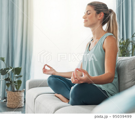Meditation, yoga and woman doing exercise for fitness, health and peace while sitting in lotus on sofa in lounge at home. Russia female calm and zen during wellness, mindfulness or spiritual practice Meditation, yoga and woman doing exercise for fitness, health and peace while sitting in lotus on sofa in lounge at home. Russia female calm and zen during wellness, mindfulness or spiritual practice 95039499