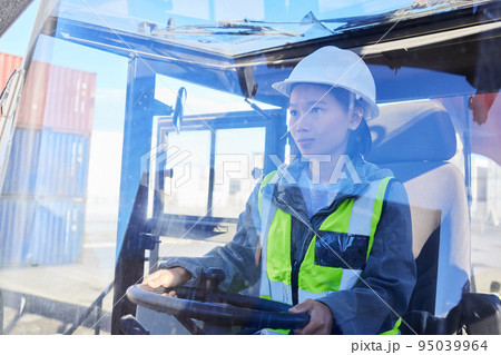Asian woman, logistics and machine for industry shipping at work for transportation in container yard. An engineer working in industrial warehouse with transport machinery for cargo shipment Asian woman, logistics and machine for industry shipping at work for transportation in container yard. An engineer working in industrial warehouse with transport machinery for cargo shipment 95039964