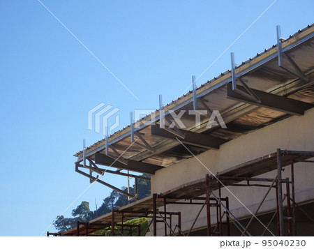 MELAKA, MALAYSIA - SEPTEMBER 16, 2022: Installation of the aluminum cladding frame at the end of the roof is underway. The metal decking roof system is equipped with a heat-resistant silsalation layer 95040230