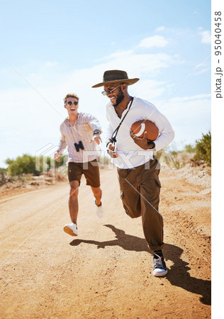 Football, friends and playing a game with man friends running on a dirt road or the dessert out in nature during the day. Running, fun and summer sport with a male and friend on a sand footpath 95040458