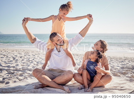 Love, beach and a happy family bonding in sand, playing and having fun on summer vacation in Mexico. Kids, parents and ocean view with excited girl enjoying playful game with her mother and father 95040650