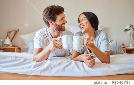 Happy morning, coffee and couple smile in bed feeling relax, love and happiness in a bedroom home. Smiling boyfriend and girlfriend together in a house laughing and spending quality time drinking tea 95040755