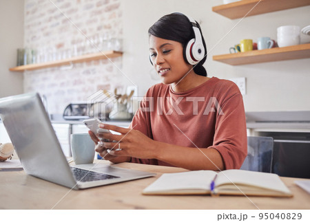 Social media, music and business woman typing an email on a mobile app on phone working on laptop in house. Remote entrepreneur or worker reading on the internet, listening to radio and planning work 95040829
