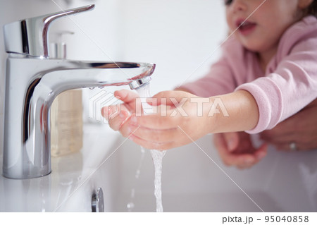 Hand, water and cleaning with a girl and her mother washing her hands under a tap for hygiene and sanitation during covid in their home. Children, health and grooming in the bathroom of a house Hand, water and cleaning with a girl and her mother washing her hands under a tap for hygiene and sanitation during covid in their home. Children, health and grooming in the bathroom of a house 95040858