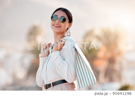 Fashion, style and shopping bags with a woman luxury sunglasses on an urban city street enjoying travel. Stylish, tourism and rich arab female customer or tourist happy about sale discount purchase 95041296
