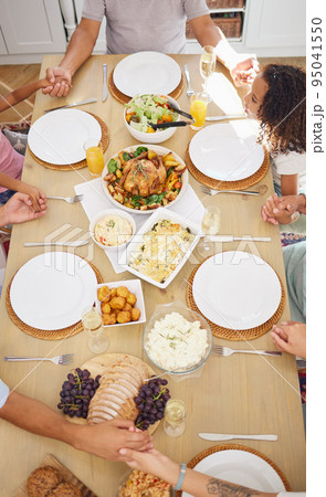 Pray, food and family friends dinner at a table with gratitude, love and religion faith before eating. Praying at a meal as a spiritual and christian practice holding hands together for worship Pray, food and family friends dinner at a table with gratitude, love and religion faith before eating. Praying at a meal as a spiritual and christian practice holding hands together for worship 95041550