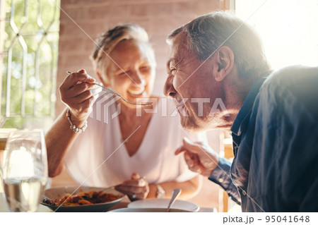 Couple, love and food with a senior man and woman on a date in a restaurant while eating on holiday. Travel, romance and dating with an elderly male and female pensioner enjoying a meal together 95041648