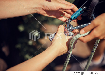 Hands, sports and climbing gear for mountain adventure preparing rope and cables for outdoor climb. Hand of a climber tying cable for heath and safety for sport exercise in nature trekking or hiking Hands, sports and climbing gear for mountain adventure preparing rope and cables for outdoor climb. Hand of a climber tying cable for heath and safety for sport exercise in nature trekking or hiking 95042796