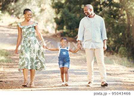 Black family, love and active parents walking with their child through nature for an adventure and outdoor fun. Happy african man and woman with daughter enjoying travel, vacation and leisure walk Black family, love and active parents walking with their child through nature for an adventure and outdoor fun. Happy african man and woman with daughter enjoying travel, vacation and leisure walk 95043466