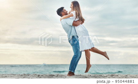 Happy couple at beach lift and hug to celebrate love on romantic sunset tropical ocean water Bali luxury vacation travel or holiday. Woman and man dating and celebration for engagement announcement 95044881