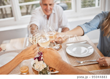 Family, wine and toast in celebration of of a holiday or good news at table, happy and cheerful in their home. Relax, smiling and excited people cheers before lunch, hungry and ready to share a meal 95044883