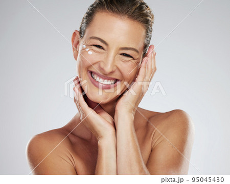 Model, cream and skincare with hands on mature face in beauty, wellness and happiness with smile in portrait. Woman, skin and happy for dermatology, cosmetic and health against studio background Model, cream and skincare with hands on mature face in beauty, wellness and happiness with smile in portrait. Woman, skin and happy for dermatology, cosmetic and health against studio background 95045430