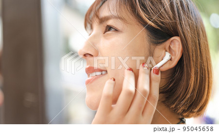 イヤフォンで音楽を聴きながらスマホを操作する女性 95045658