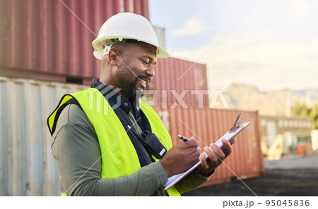 Logistics, inspection, shipping and black man writing notes working at storage container port. African industrial manager happy with documents for cargo at an outdoor manufacturing warehouse 95045836