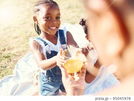 Happy girl, juice and smile in family picnic fun and joy in happiness on a warm summer day in nature. Black child smiling for fresh cold healthy beverage in the hot outdoors with parent and sibling Happy girl, juice and smile in family picnic fun and joy in happiness on a warm summer day in nature. Black child smiling for fresh cold healthy beverage in the hot outdoors with parent and sibling 95045976