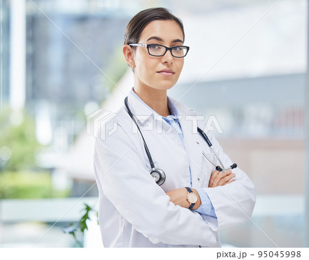 Portrait of a doctor with arms crossed in her consultation office with glasses and a stethoscope. Woman healthcare professional standing in a room in a medicare hospital, clinic or surgery center. 95045998